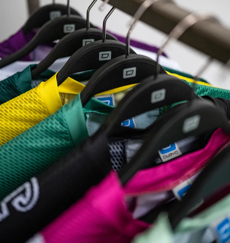 Several colorful, customized sportswear items hang on black hangers.