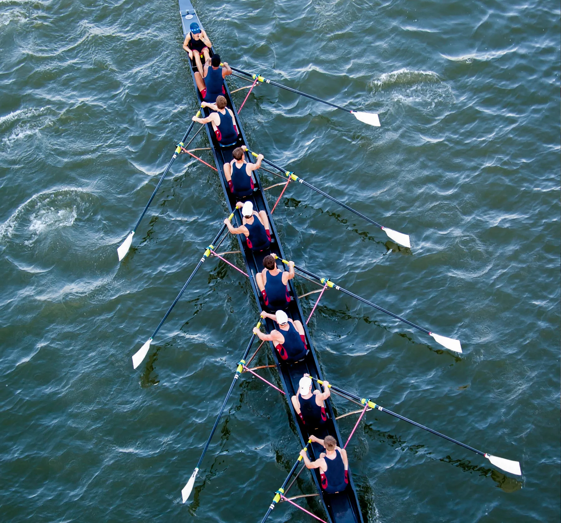 A group of rowers in matching sportswear rowing in sync on a body of water.